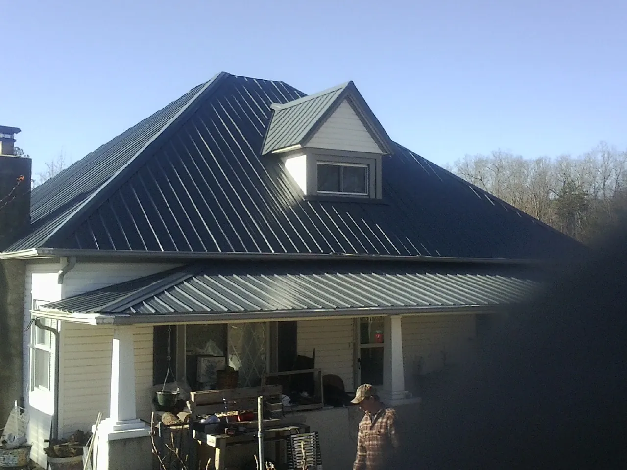Dark blue standing seam metal roof with a dormer above a front porch in Maben