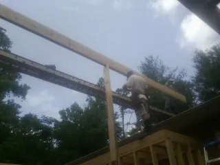 Carpenter setting a ridge beam over a new addition frame — Ice Dam Removal by Roofing Brothers in Maben
