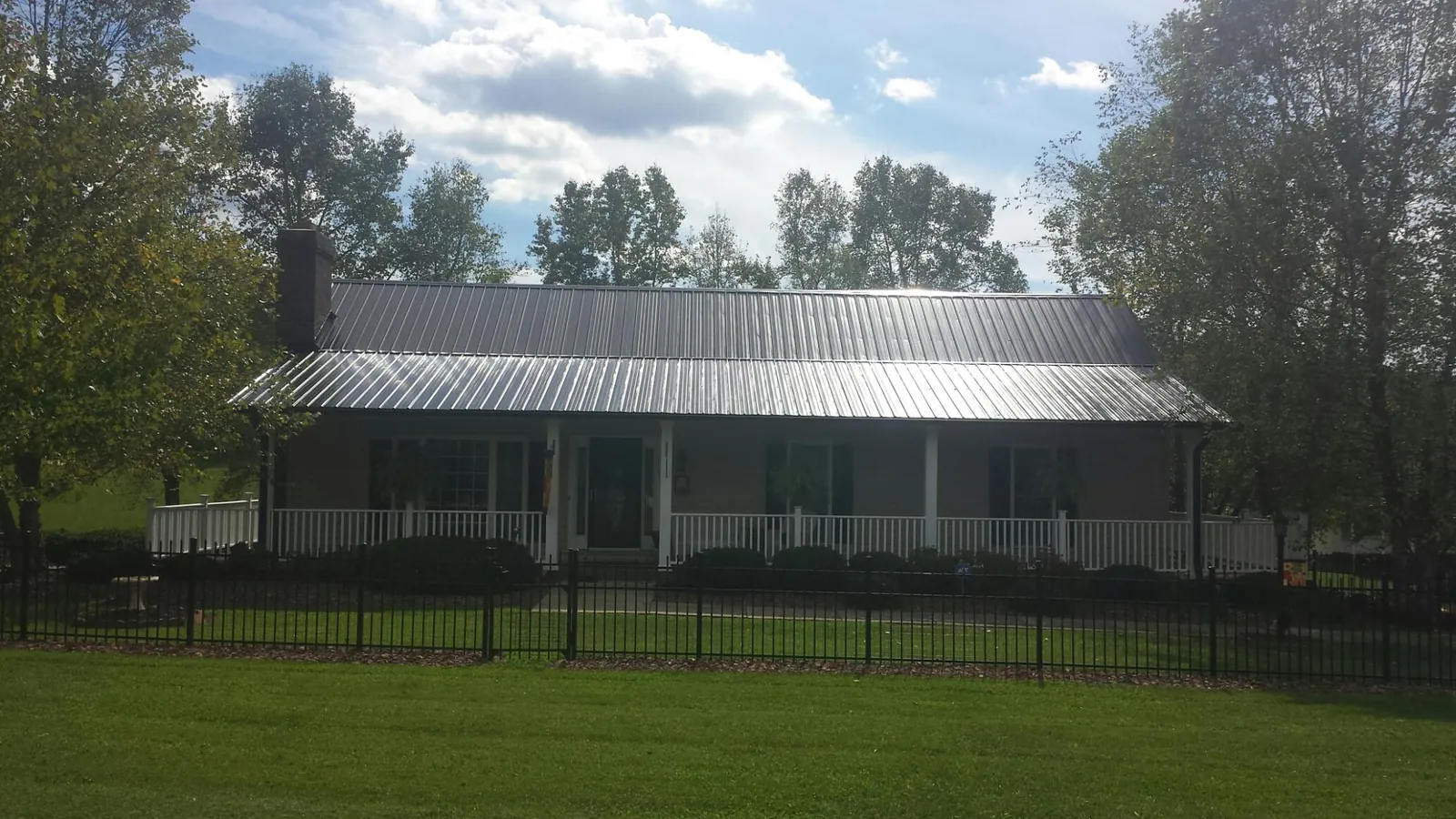 Gray metal roof on a brick ranch with a full width front porch — Gutter Guard Installation work by our crew in Maben
